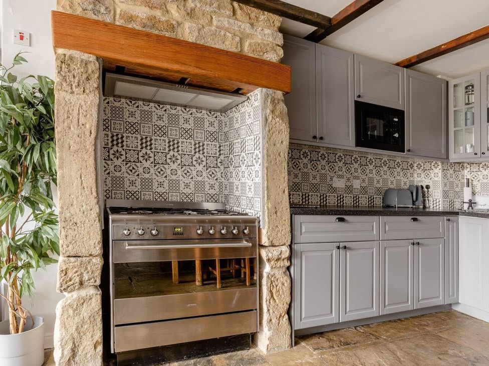 A kitchen with a stove, cabinets and decorative tiles at OldMill 2Bed Sleeps6 PrivateGarden OptionalHotTub in Oakworth