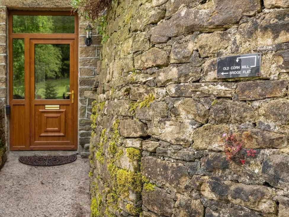 A door and stone wall with a nameplate at Old Corn Mill, Oakworth