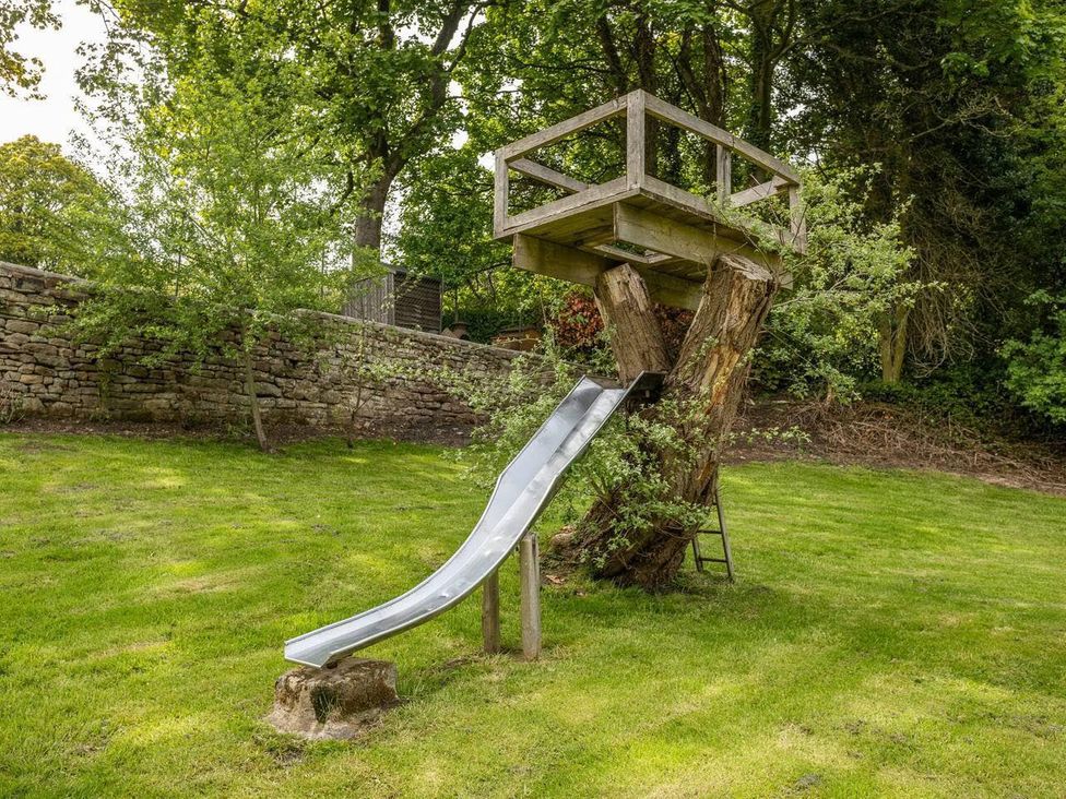 A slide and wooden platform in a garden at OldMill 2Bed Sleeps6 PrivateGarden OptionalHotTub in Oakworth