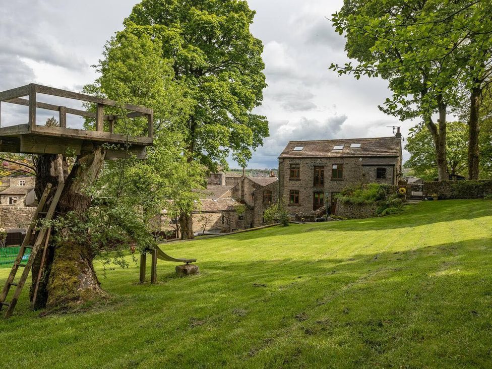 An outdoor view of a garden with a treehouse and buildings at OldMill 2Bed Sleeps6 PrivateGarden OptionalHotTub in Oakworth