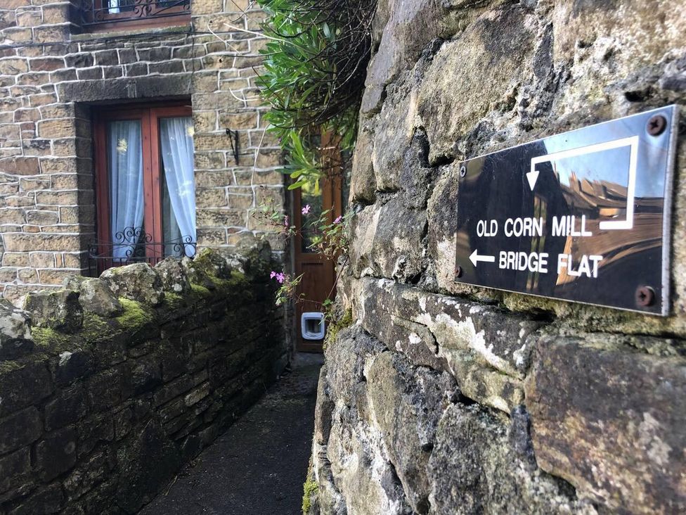 An outdoor pathway next to a stone wall with a sign at OldMill 2Bed Sleeps6 PrivateGarden OptionalHotTub in Oakworth