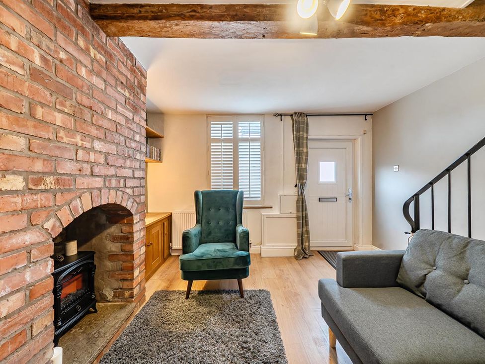 A living room with a brick fireplace and seating at Quaint Cottage in Charming Evesham