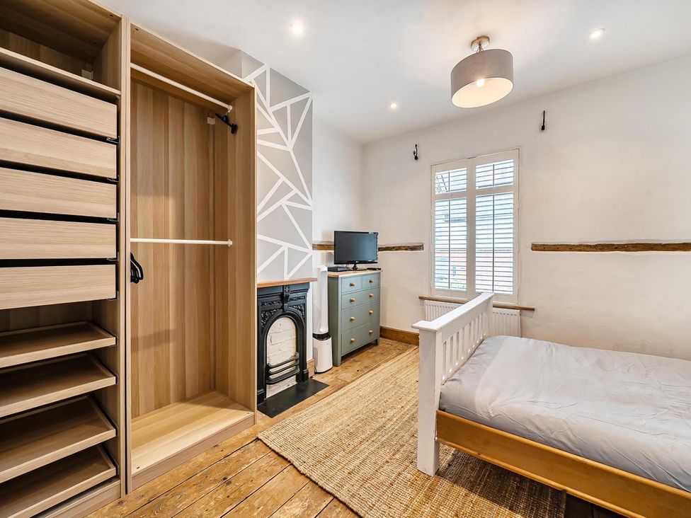 A bedroom with a bed and wardrobe at Quaint Cottage in Charming Evesham
