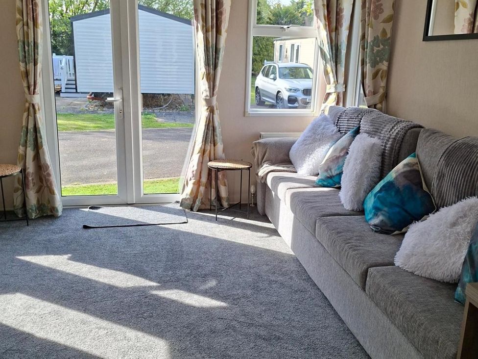 A living room with a sofa and curtains at Homely Caravan in Skegness