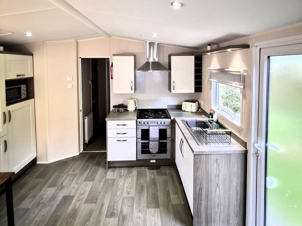A kitchen with a stove, sink, and cabinets at Homely Caravan in Skegness