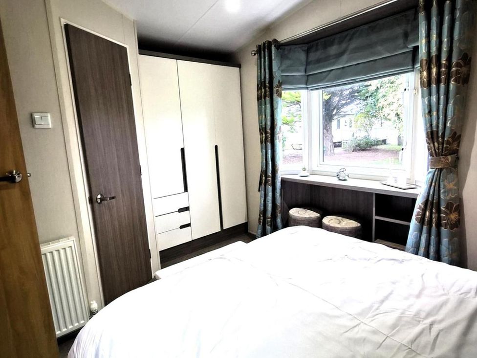 A bedroom with a bed and wardrobe at Homely Caravan in Skegness
