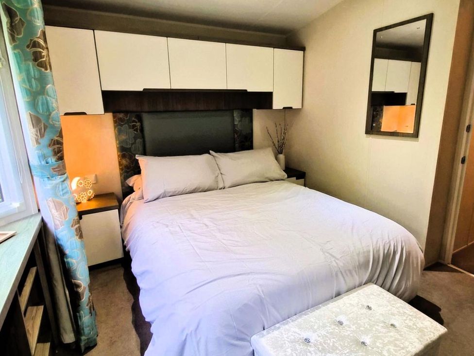 A bedroom with a bed and shelf at Homely Caravan in Skegness