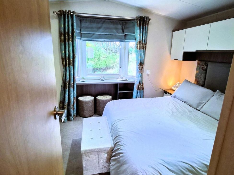 A bedroom with a bed and window at Homely Caravan in Skegness