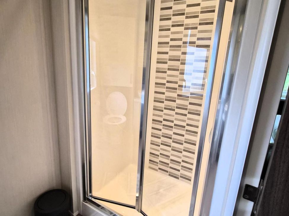 A shower and toilet in a bathroom at Homely Caravan in Skegness