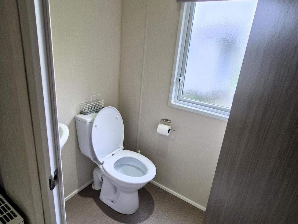 A bathroom with a toilet and sink at Homely Caravan in Skegness