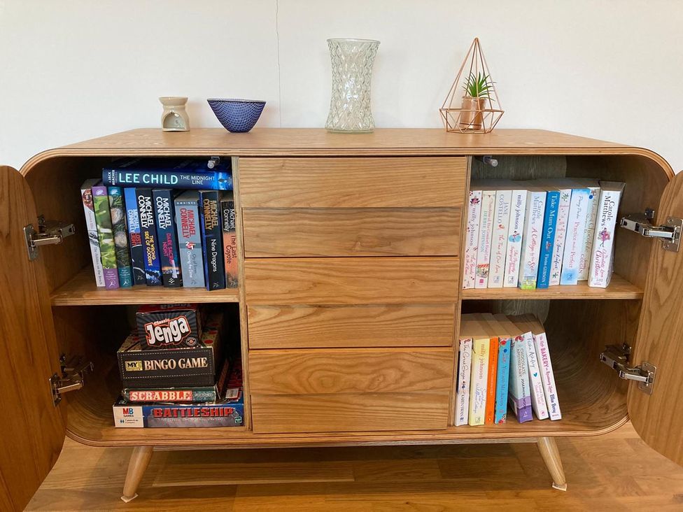 A cabinet with books and games in a living room at Tyler Hill near Canterbury