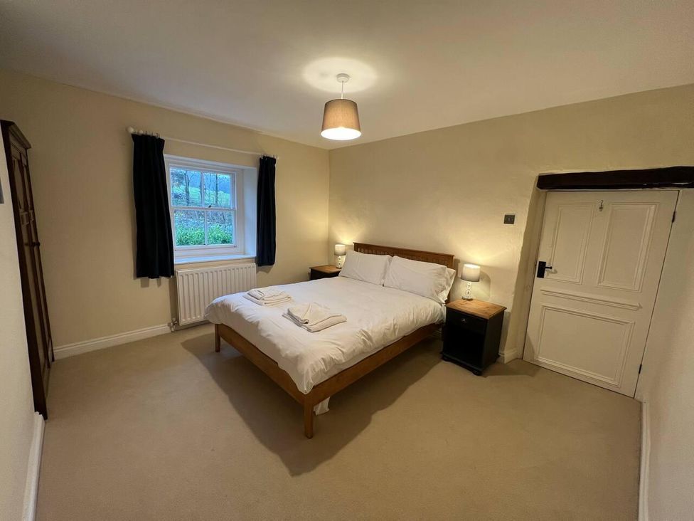 A bedroom with a bed and nightstands at House Sleeps 10 Pet friendly Parking in Caldbeck