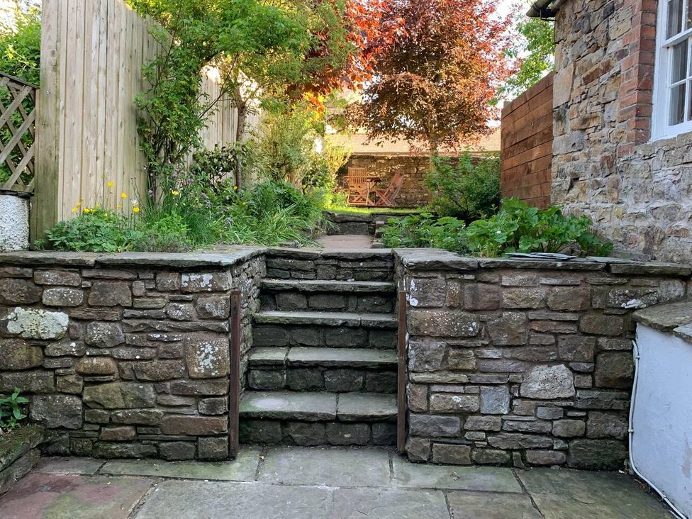 A garden with stone steps leading up to seating area at House Sleeps 10 Pet friendly Parking Caldbeck