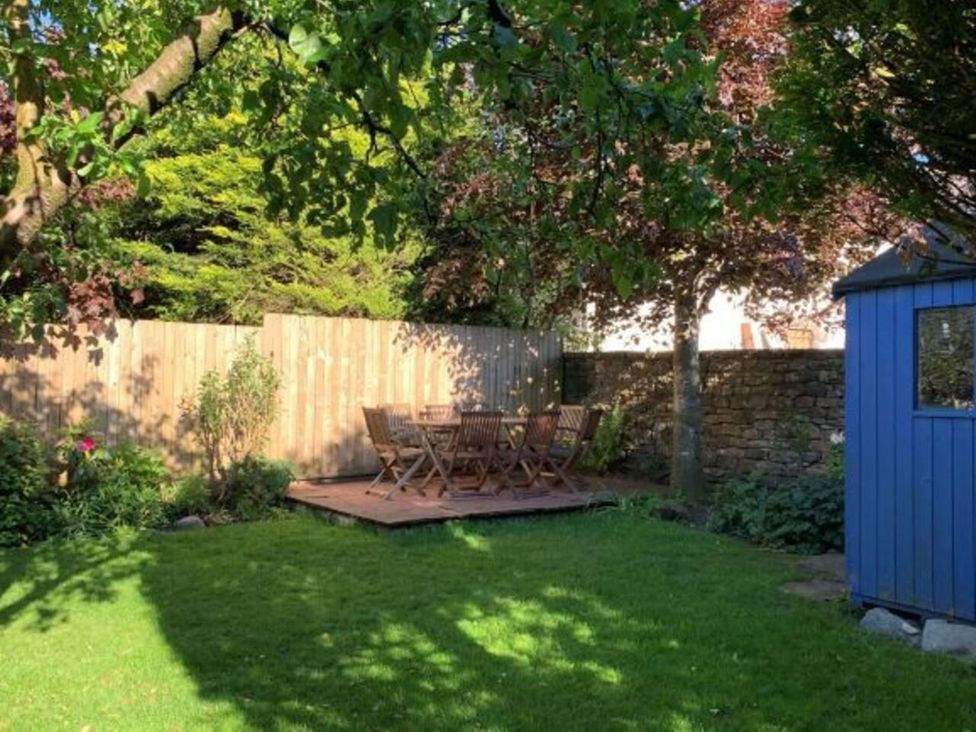 A garden with a wooden deck and seating area at House Sleeps 10 Pet friendly Parking in Caldbeck