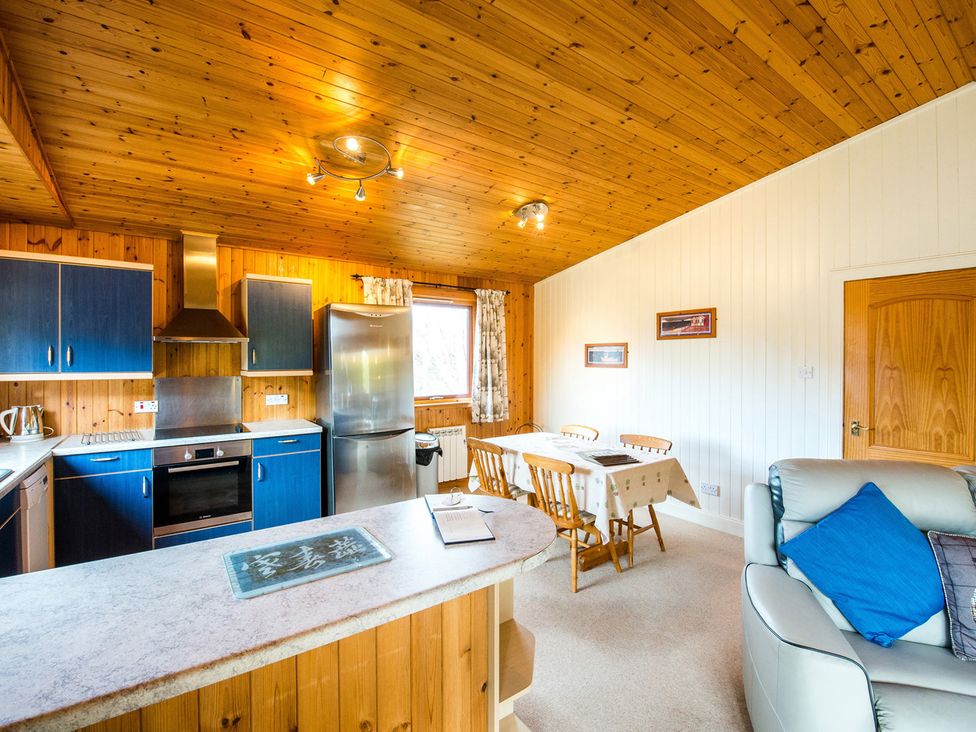 A kitchen with cabinets and a dining table at Raven Lodge with beautiful views of Loch Dochart near Crianlarich