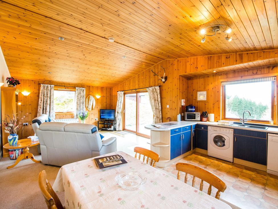 A living room with sofa and kitchen area at Raven Lodge with beautiful views of Loch Dochart near Crianlarich