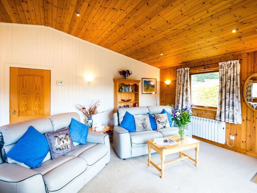 A living room with sofas and a coffee table at Raven Lodge with beautiful views of Loch Dochart near Crianlarich