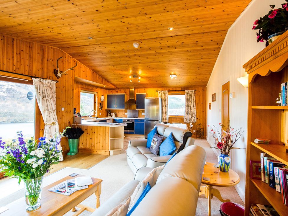 A living room with a sofa and bookshelf at Raven Lodge with beautiful views of Loch Dochart Near Crianlarich