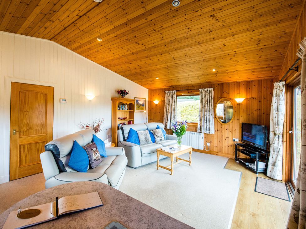 A living room with a sofa and coffee table at Raven Lodge with beautiful views of Loch Dochart near Crianlarich