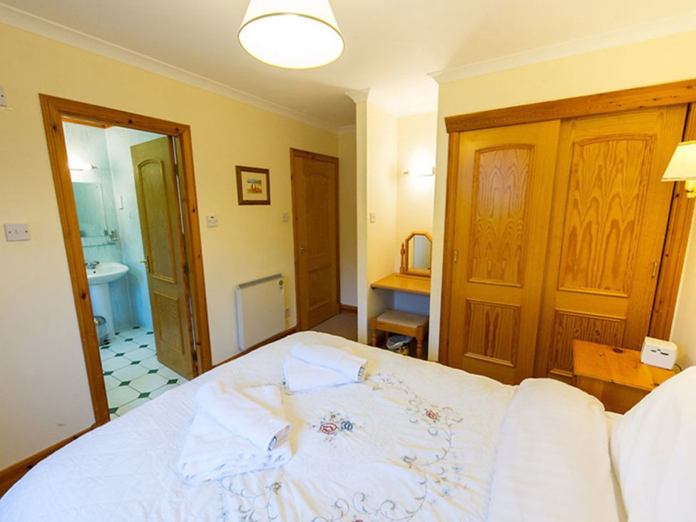 A bedroom with a bed, wardrobe, and access to a bathroom at Raven Lodge with beautiful views of Loch Dochart Near Crianlarich