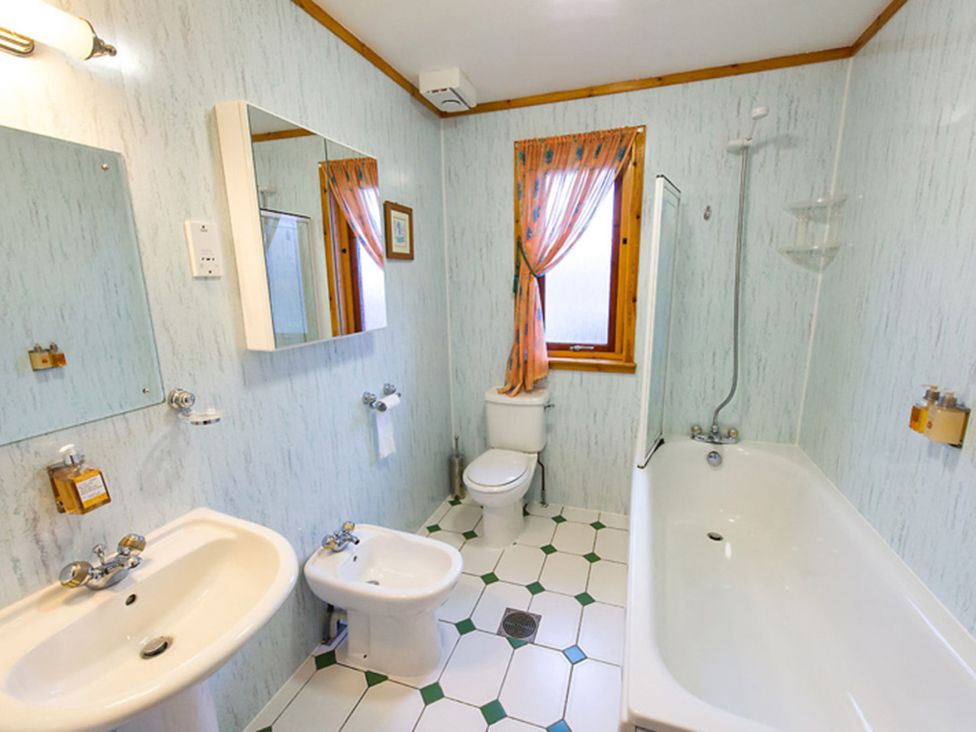 A bathroom with a bathtub, toilet, bidet, and sink at Raven Lodge with beautiful views of Loch Dochart near Crianlarich