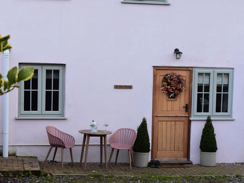 An outdoor seating area with a table and chairs at Yr Hen Beudy Barn Conversion Sleeps 4 Dogs Ok, Brodle Farm near Llansteffan