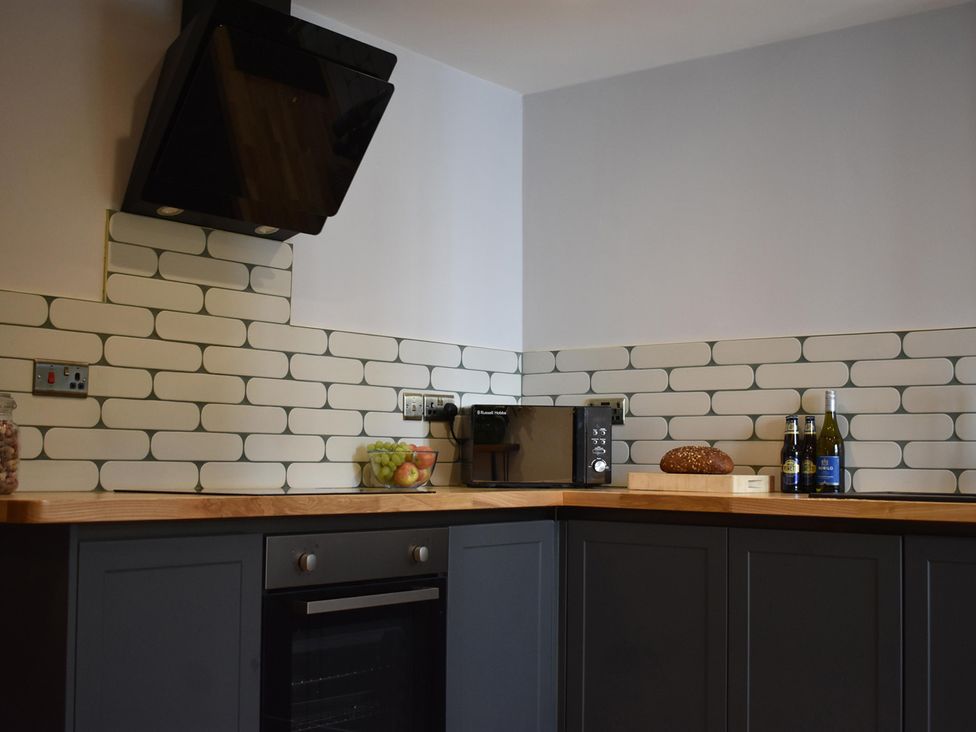 A kitchen with an oven and microwave at Yr Hen Beudy Barn Conversion Sleeps 4 Dogs Ok, Brodle Farm near Llansteffan