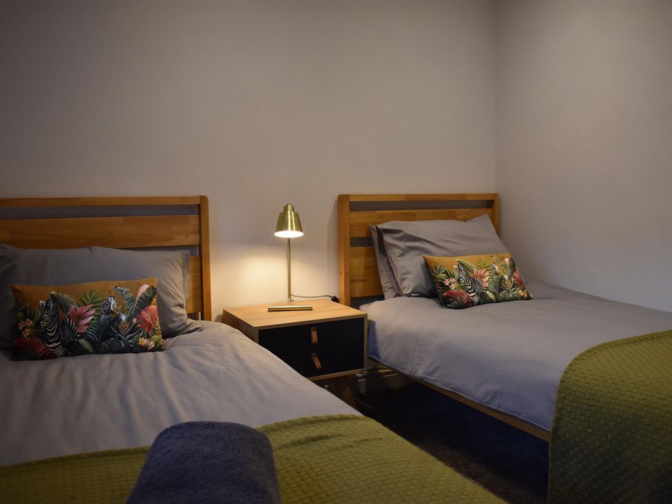 A bedroom with two beds and a lamp at Yr Hen Beudy Barn Conversion Sleeps 4 Dogs Ok near Brodle Farm near Llansteffan