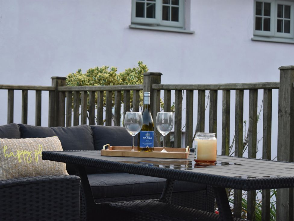 A seating area with a sofa, table, wine, and candle at Yr Hen Beudy Barn Conversion Sleeps 4 Dogs Ok, Brodle Farm near Llansteffan