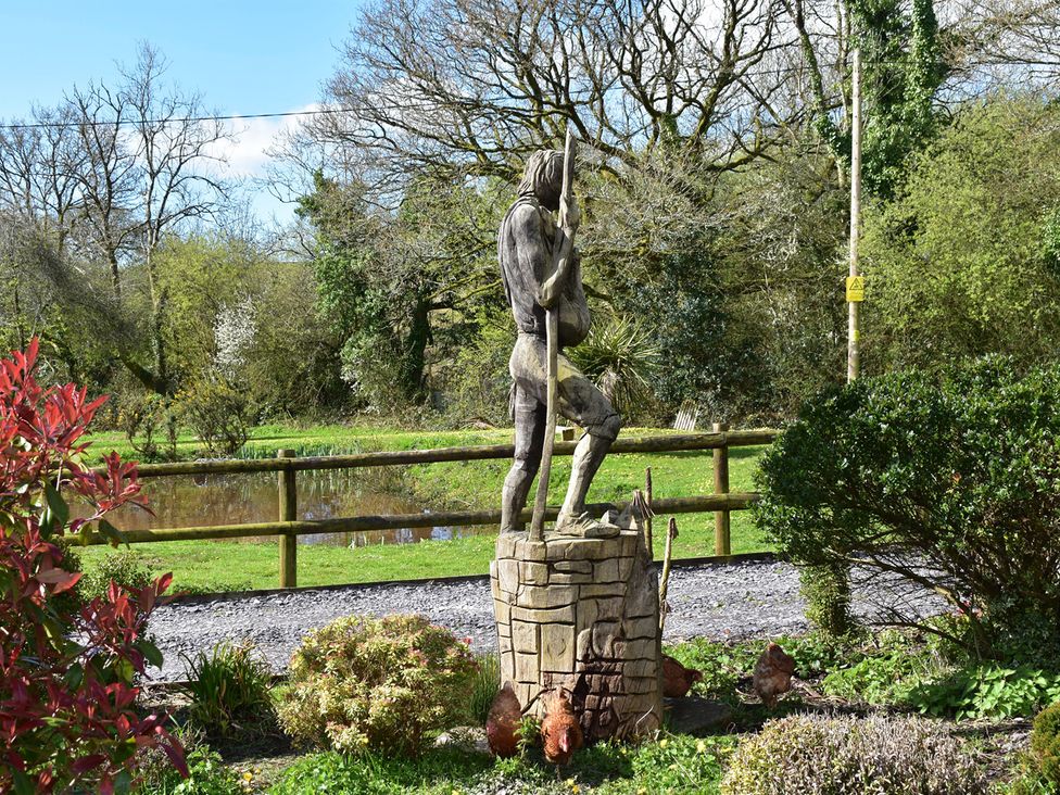 A statue in a garden with trees and a pond at Yr Hen Beudy Barn Conversion Sleeps 4 Dogs Ok in Broadle Farm near Llansteffan