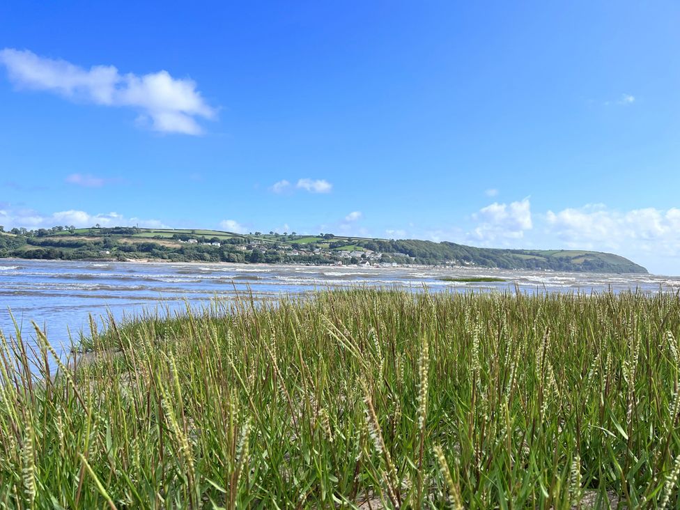A view of the sea and grass with hills in the background at Yr Hen Beudy Barn Conversion Sleeps 4 Dogs Ok, Brodle Farm near Llansteffan