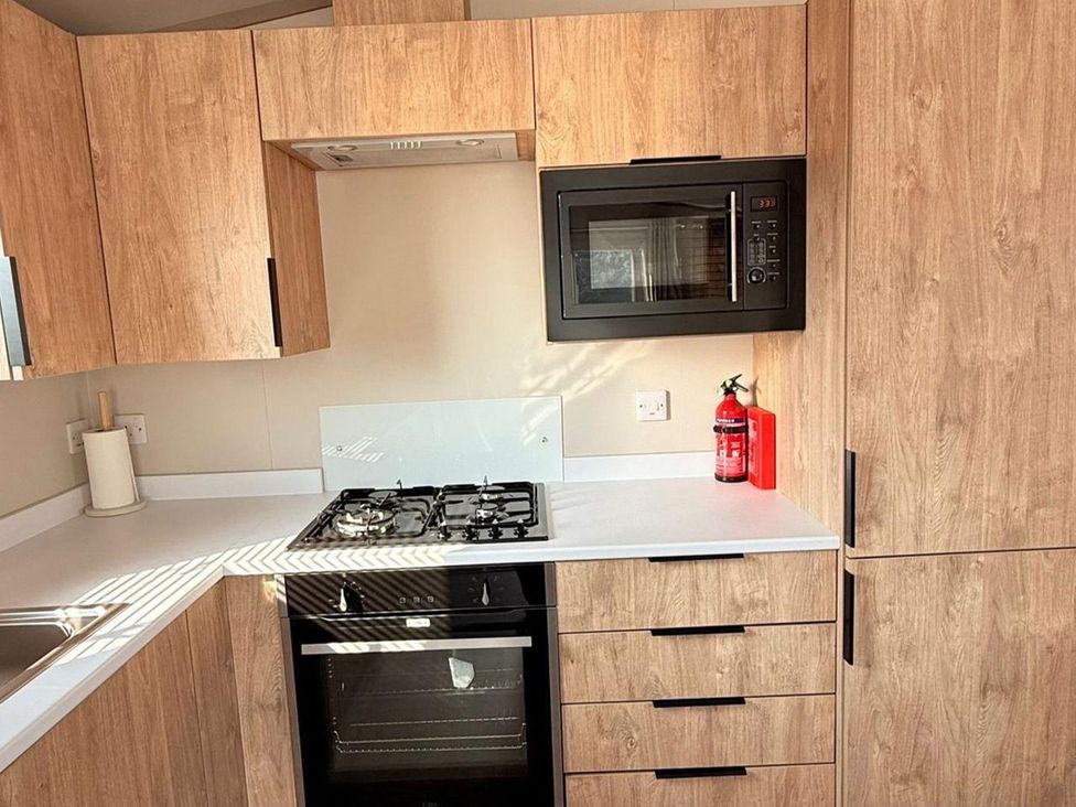A kitchen with cabinets, stove, microwave and fire extinguisher at 3Bed Sleeps 6 Parking Balcony Flamingo Land Resort near Kirkby Misperton
