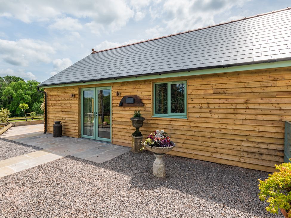 An outdoor area with a wooden building and flowers at Paddock View Barn 1Bed Sleeps 4 with Parking near Duffryn Lloff Farm