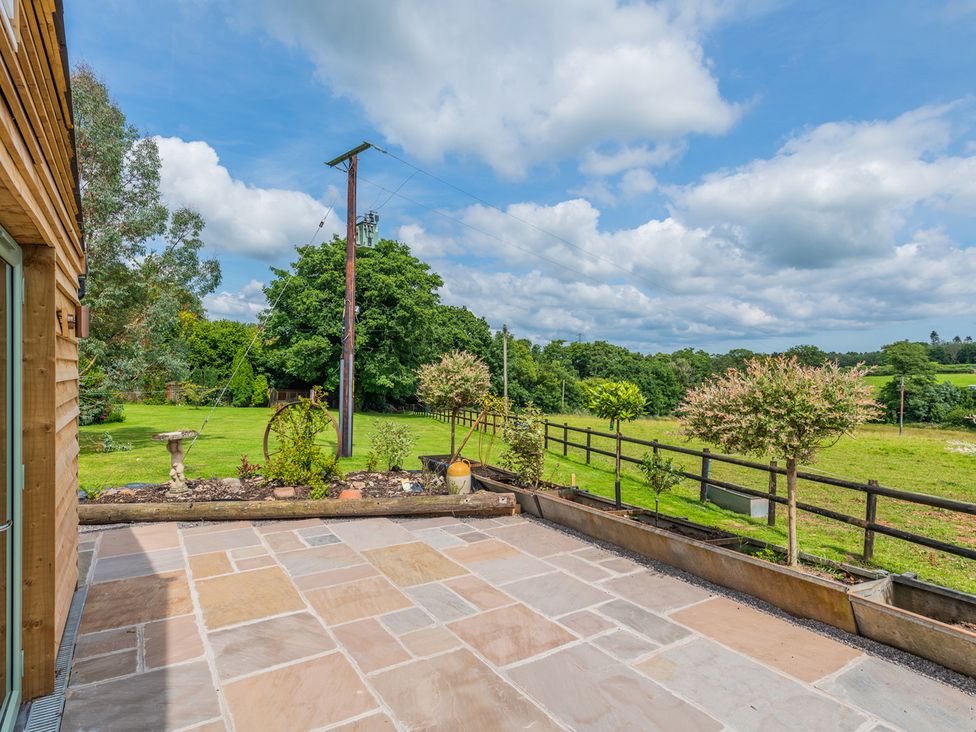 A patio with a view of a garden and trees at Paddock View Barn 1Bed Sleeps 4 with Parking near Duffryn Lloff Farm