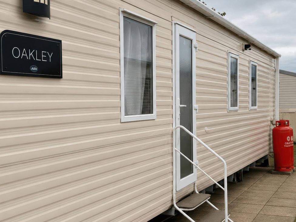 A caravan with a sign named Oakley and a gas cylinder at the entrance