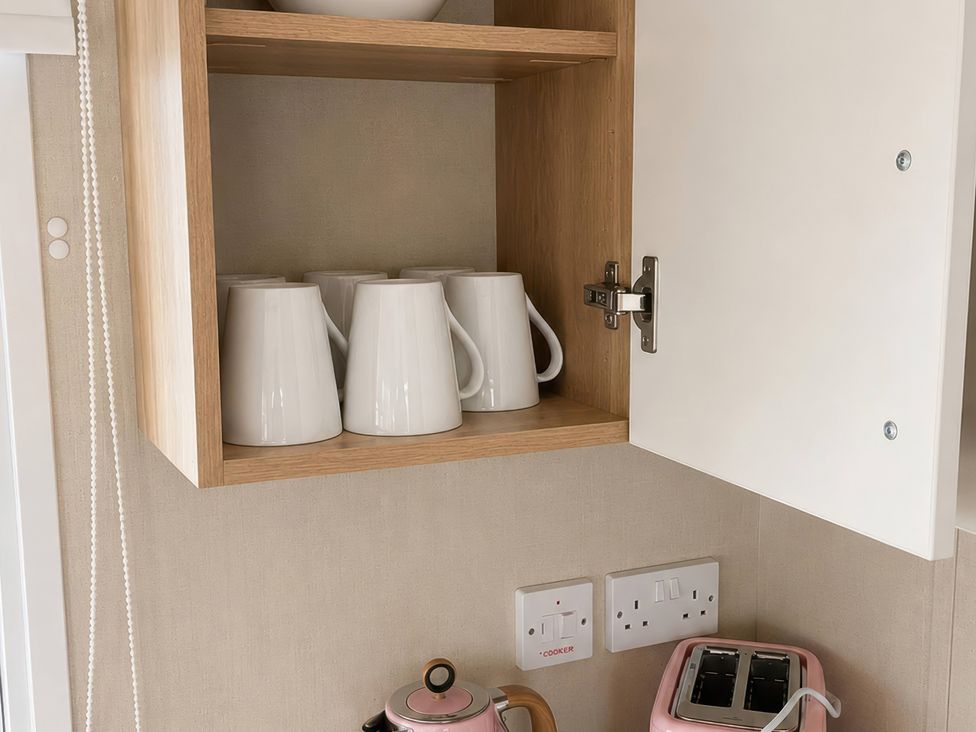 A kitchen with mugs on a shelf and a kettle and toaster on the counter at the property in location