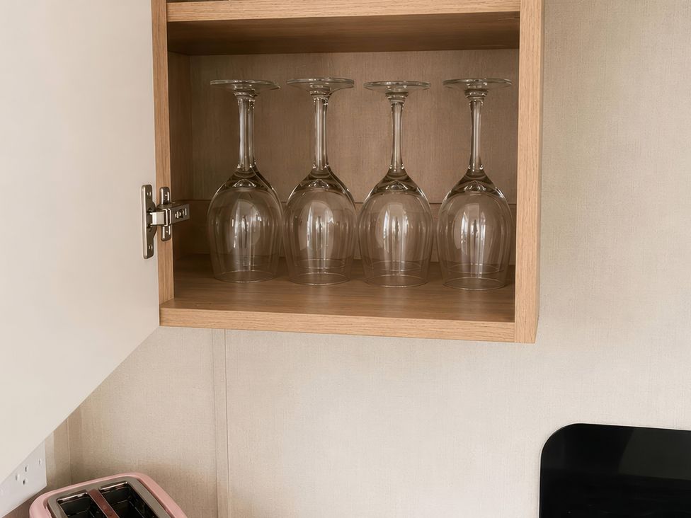 A cupboard with glasses and a toaster in the kitchen