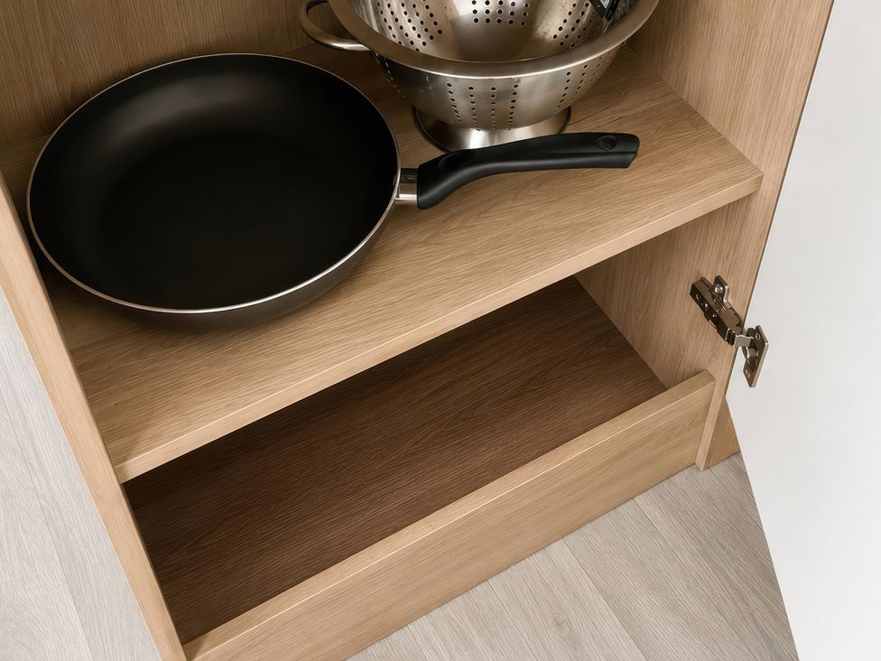 A frying pan and a colander in a kitchen cabinet at 