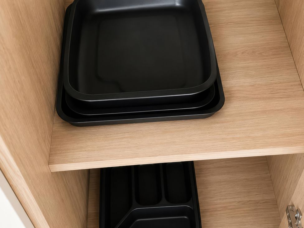 A kitchen cabinet with black trays stacked inside