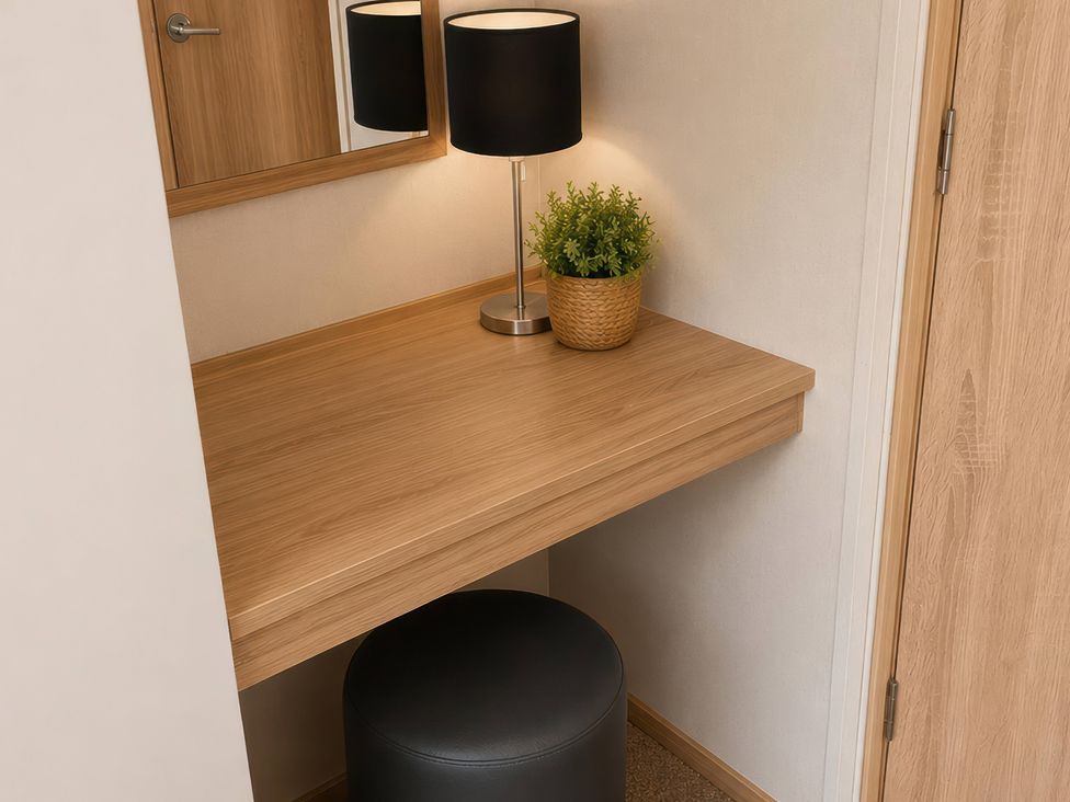 A dressing area with a desk, lamp, and plant near a mirror at a property in unspecified location