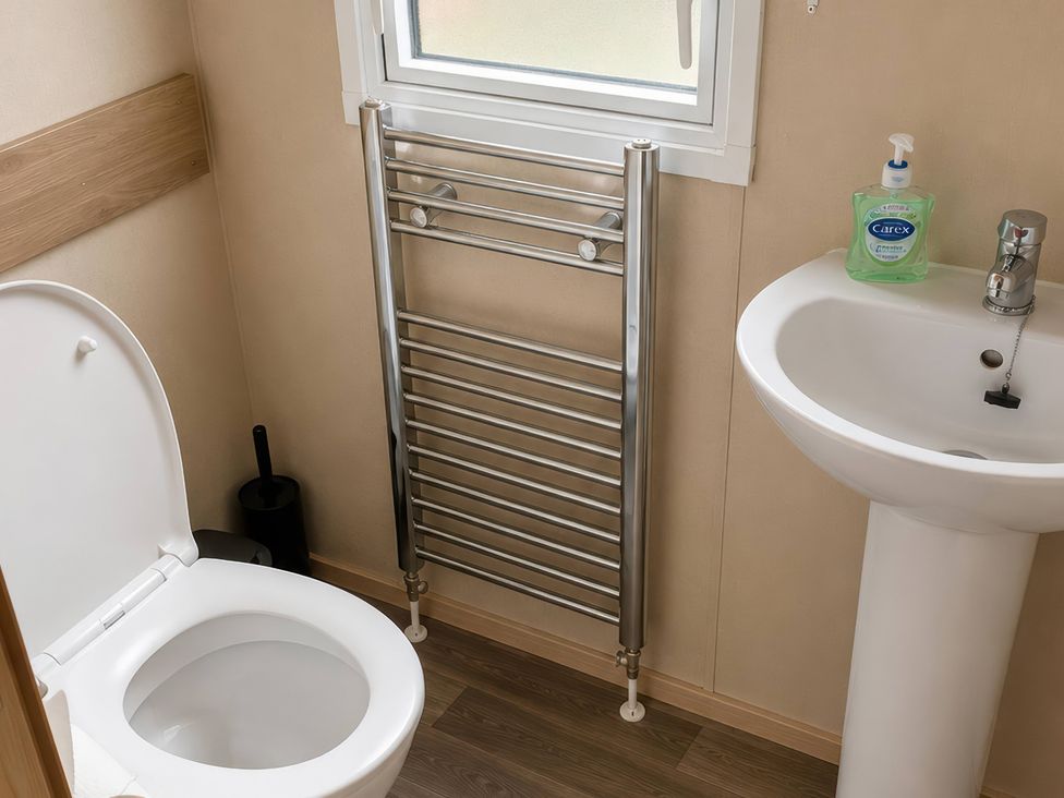 A bathroom with a toilet, sink, and towel rail at 
