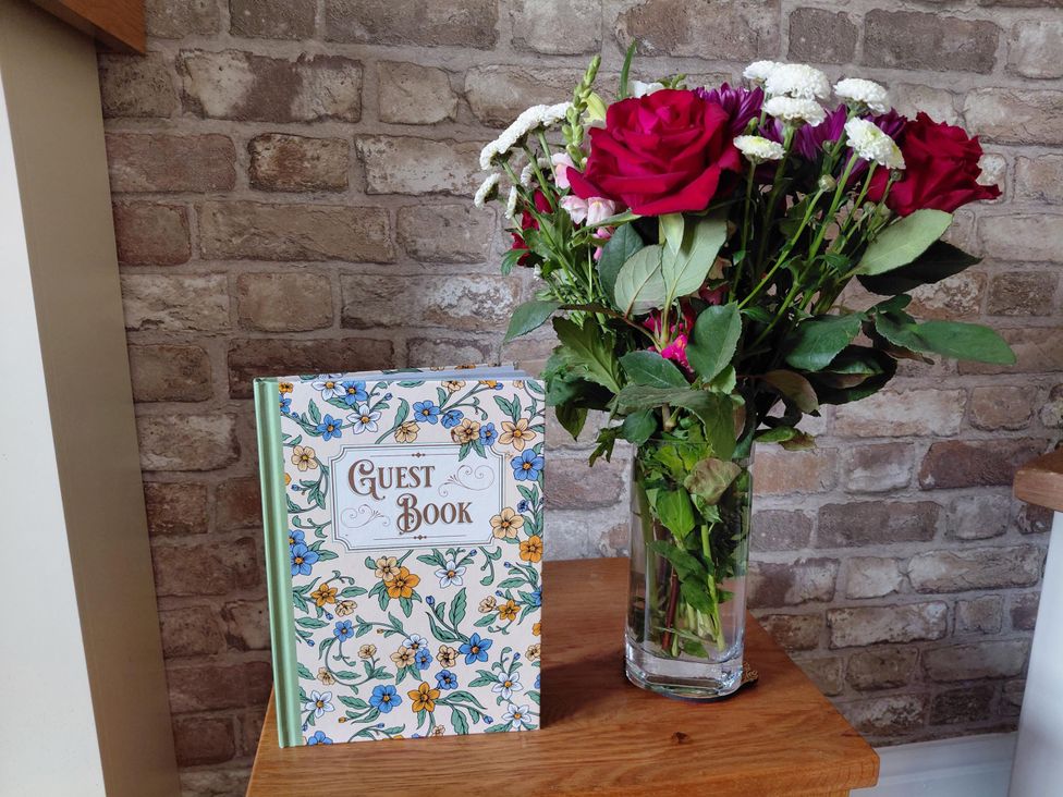 A guest book and a vase of flowers on a table at Central Ripon Sleeps 3 Garden Pet Friendly Ripon