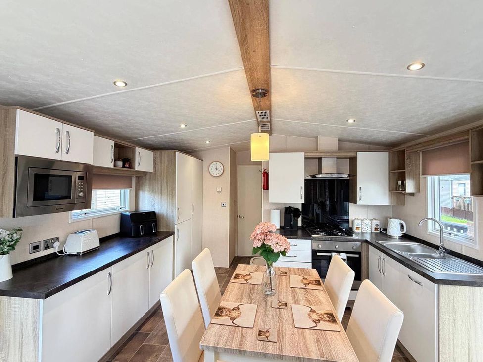 A kitchen with appliances and dining table at Lillardsedge Luxury Caravan Sleeps 6 with Parking near Lilliardsedge Holiday Park