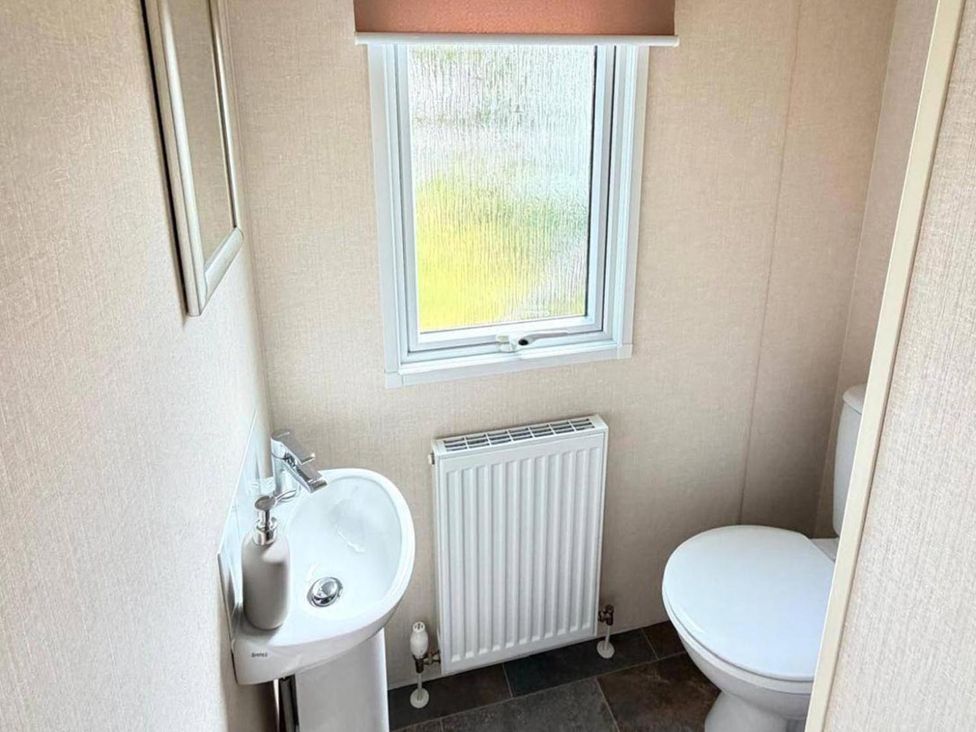 A bathroom with a sink, toilet, and window at Lillardsedge Luxury Caravan Sleeps 6 with Parking near Lilliardsedge Holiday Park