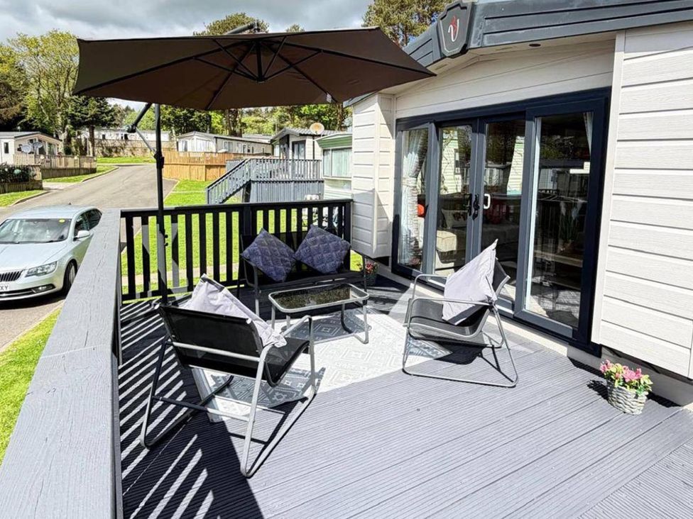 An outdoor area with chairs and an umbrella at Lillardsedge Luxury Caravan Sleeps 6 with Parking Lilliardsedge Holiday Park near St Boswells
