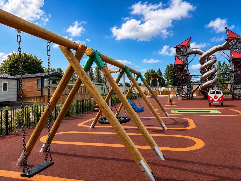 A playground with swings and a climbing structure at Lillardsedge Luxury Caravan Sleeps 6 with Parking Lilliardsedge Holiday Park near St Boswells