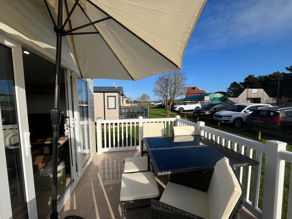 An outdoor seating area with a table and chairs at Surfside Bliss Cayton Bay Park caravan in Cayton Bay