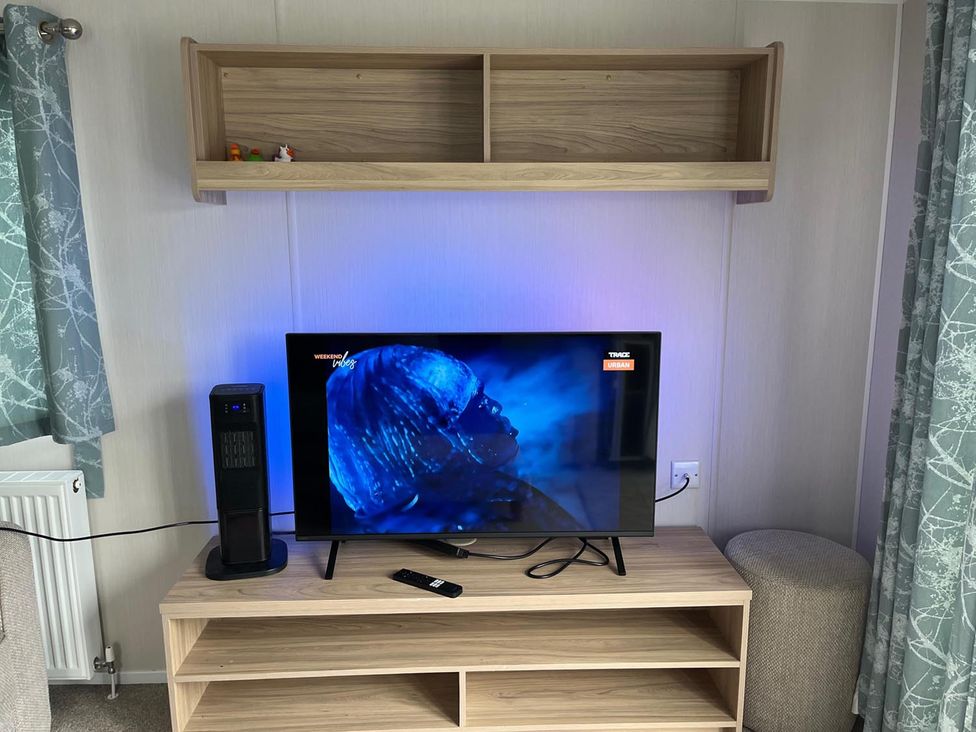 A living room with a television and an entertainment unit at Surfside Bliss Cayton Bay Park caravan