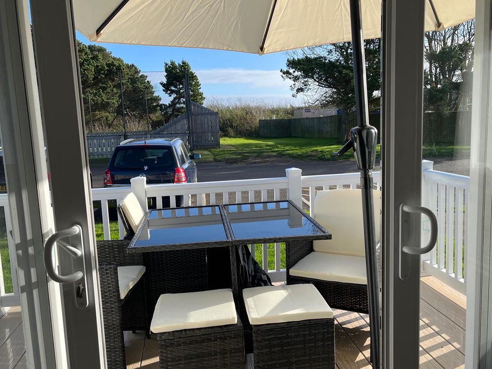 An outdoor seating area with a table and chairs at Surfside Bliss Cayton Bay Park caravan Cayton Bay