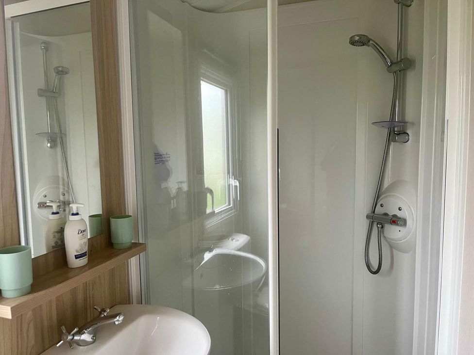 A bathroom with a shower and sink at Surfside Bliss Cayton Bay Park caravan, Cayton Bay